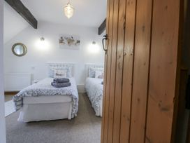 A bedroom with two beds and a mirror at Ty Gwennol in Llanfaethlu