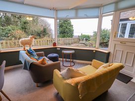 A conservatory with seating and a coffee table at Yewbarrow Cottage in Grange-Over-Sands