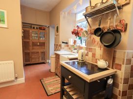 A kitchen with a sink, stove, and storage cabinets at Yewbarrow Cottage in Grange-Over-Sands