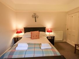 A bedroom with a bed, nightstand, lamps and door at Yewbarrow Cottage in Grange-Over-Sands