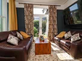 A living room with two brown leather sofas facing each other a wooden coffee table and floral curtains at The Woodlands in Berrynarbor