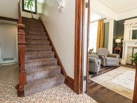 A carpeted staircase next to a sitting room with two armchairs a rug and a fireplace at The Woodlands in Berrynarbor