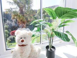 A window sill with a white teddy bear and a potted green plant at The Woodlands in Berrynarbor