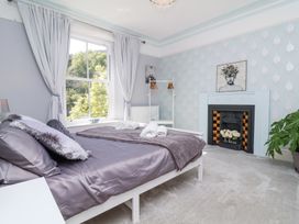 A bedroom with a bed cushions and folded towels near a window and a fireplace with flowers and a plant at The Woodlands in Berrynarbor