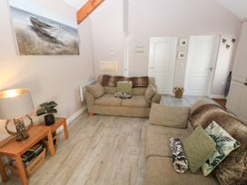 A living room with two beige sofas wooden table lamp plant paintings on the wall and a light wood floor at Love Cottage in Tenby