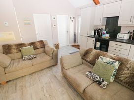 A living room with two beige sofas and kitchen cabinets in the background at Love Cottage in Tenby
