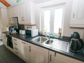A kitchen countertop with a sink microwave toaster coffee machine and kettle at Love Cottage in Tenby