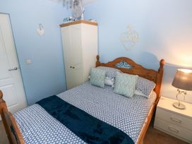 A bedroom with a wooden bed a wardrobe a nightstand with a lamp and a wall decoration saying love at Love Cottage in Tenby