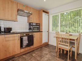A kitchen with cabinets, oven, microwave, and dining table at 49 Atlantic Reach in Newquay