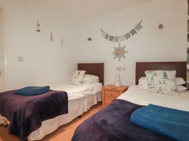 A bedroom with two beds and a bedside table at 49 Atlantic Reach Newquay