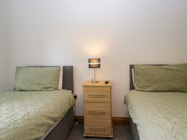 A bedroom with two beds and a nightstand at Sherriff in Troutbeck, near Keswick