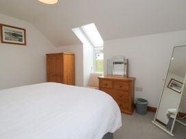 A bedroom with a bed, wooden cabinet, and mirror at Sherriff in Troutbeck, near Keswick