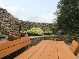 A garden with a wooden table and stone wall at Sherriff in Troutbeck, near Keswick