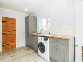 A laundry room with a washing machine and sink at Afallon Llanbedrog