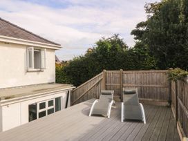 A deck area with sun loungers and a view of foliage at Afallon in Llanbedrog