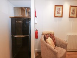 A fridge, microwave, armchair, and fire extinguisher at Orchard Lodge in Bolney