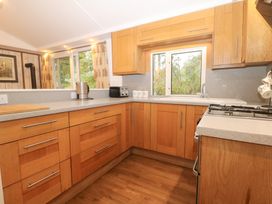 A kitchen with wooden cabinets and kitchen appliances at Orchard Lodge in Bolney