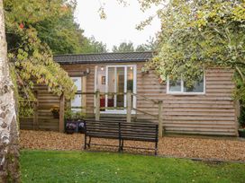 A wooden cabin with a bench and steps at Orchard Lodge in Bolney