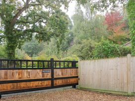 A wooden gate and fence with trees in the background at Orchard Lodge in Bolney