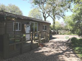 A wooden cabin with a deck and trees at Orchard Lodge in Bolney