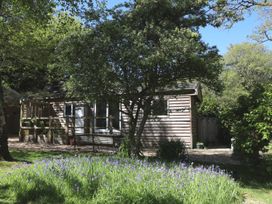 A cabin with a bench and flowers in an outdoor area at Orchard Lodge in Bolney
