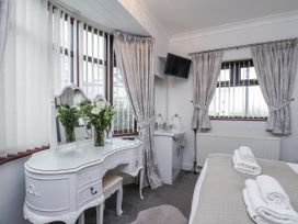 A bedroom with a vanity and fresh flowers at Beachcrest in Whitby