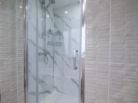 A shower with glass enclosure and tiled walls at Beachcrest in Whitby