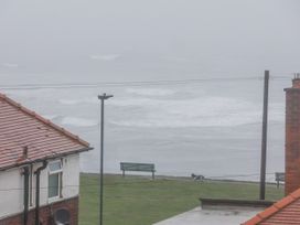 View of ocean and grassy area with a bench at Beachcrest in Whitby