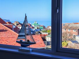 A sailboat on a windowsill with a view of the sea and houses at Beachcrest in Whitby