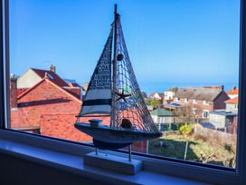A sailboat decoration on a windowsill with a view of houses and the ocean at Beachcrest in Whitby