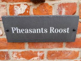 A black slate house name sign on a red brick wall with the text Pheasants Roost at Pheasant's Roost in Lelley near Burton Pidsea
