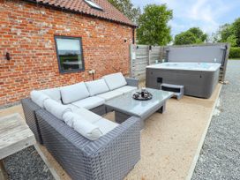 An outdoor seating area with a wicker sofa and coffee table next to a hot tub outside a brick building at Pheasant's Roost in Lelley near Burton Pidsea