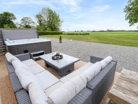 An outdoor patio with a hot tub, wicker sofas with cushions and a glass top coffee table at Pheasant's Roost in Lelley near Burton Pidsea