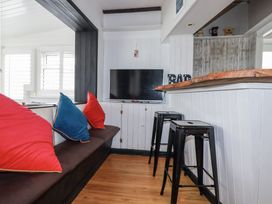A living room with a television and bar stools at The Three Tees in Newquay