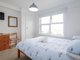 A bedroom with a bed and a chair at The Three Tees in Newquay