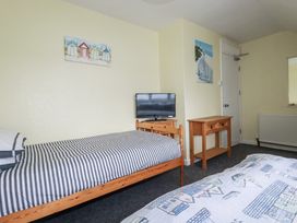 A bedroom with a single bed and a double bed and a television at The Three Tees in Newquay