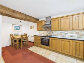 A kitchen with wooden cabinets and dining table at The Roundhouse in Warbstow