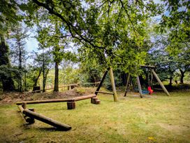 An outdoor play area with swings and a wooden structure at Beech Cottage Warbstow