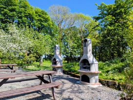 An outdoor area with two barbecues and picnic benches at Little Leighs in Warbstow