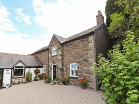 A stone house with flower pots by the door and windows at Pen Y Bont in Llanfair Talhaiarn