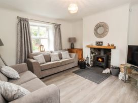 A living room with sofas a wood burning stove and a television at Pen Y Bont in Llanfair Talhaiarn