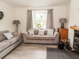 A living room with two sofas a wooden side table lamps curtains and a fireplace at Pen Y Bont in Llanfair Talhaiarn