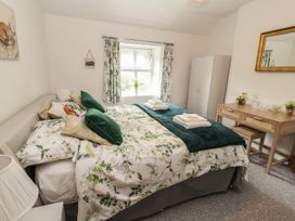 A bedroom with a double bed green and white bedding desk and wardrobe at Pen Y Bont in Llanfair Talhaiarn