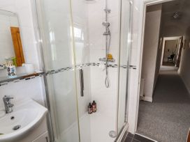 A bathroom with a glass shower enclosure a sink and a hallway visible outside the door at Pen Y Bont in Llanfair Talhaiarn