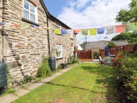 A garden area with a stone house and green grass with outdoor furniture and colorful flags at Pen Y Bont in Llanfair Talhaiarn