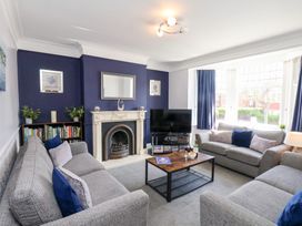 A living room with grey sofas a wooden coffee table a fireplace a television and blue accent walls at North Beach Lodge in Scarborough