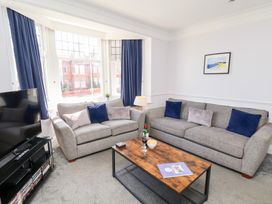 A living room with two grey sofas blue curtains and a wooden coffee table at North Beach Lodge in Scarborough