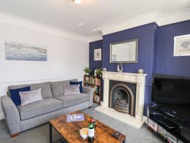 A living room with a grey sofa, wooden coffee table, fireplace, TV, bookshelf, and blue and white walls at North Beach Lodge in Scarborough