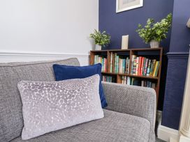 A gray sofa with two cushions next to a wooden bookshelf with books and plants at North Beach Lodge in Scarborough