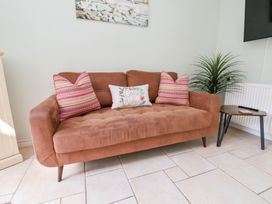 A brown sofa with three cushions beside a small wooden table and a plant at North Beach Lodge in Scarborough